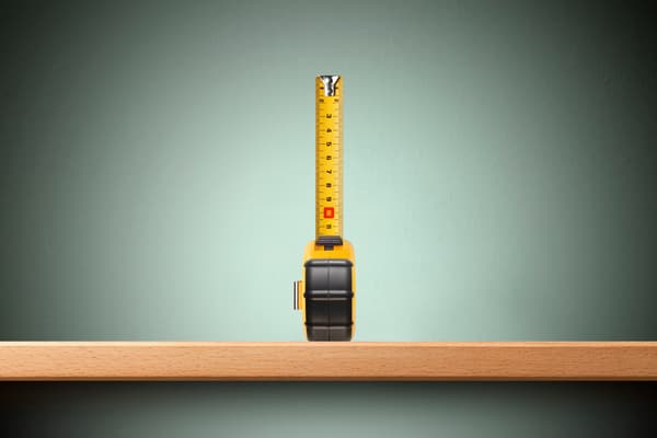 An extended tape measurer against a sage-green background An extended tape measurer against a sage-green background